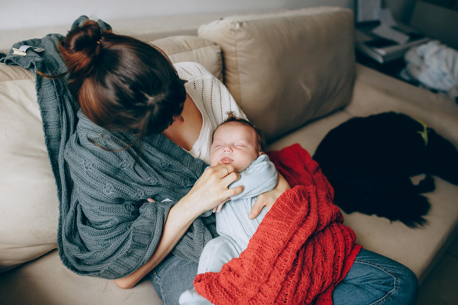 Mother sitting with newborn on the sofa in the early days of breastfeeding