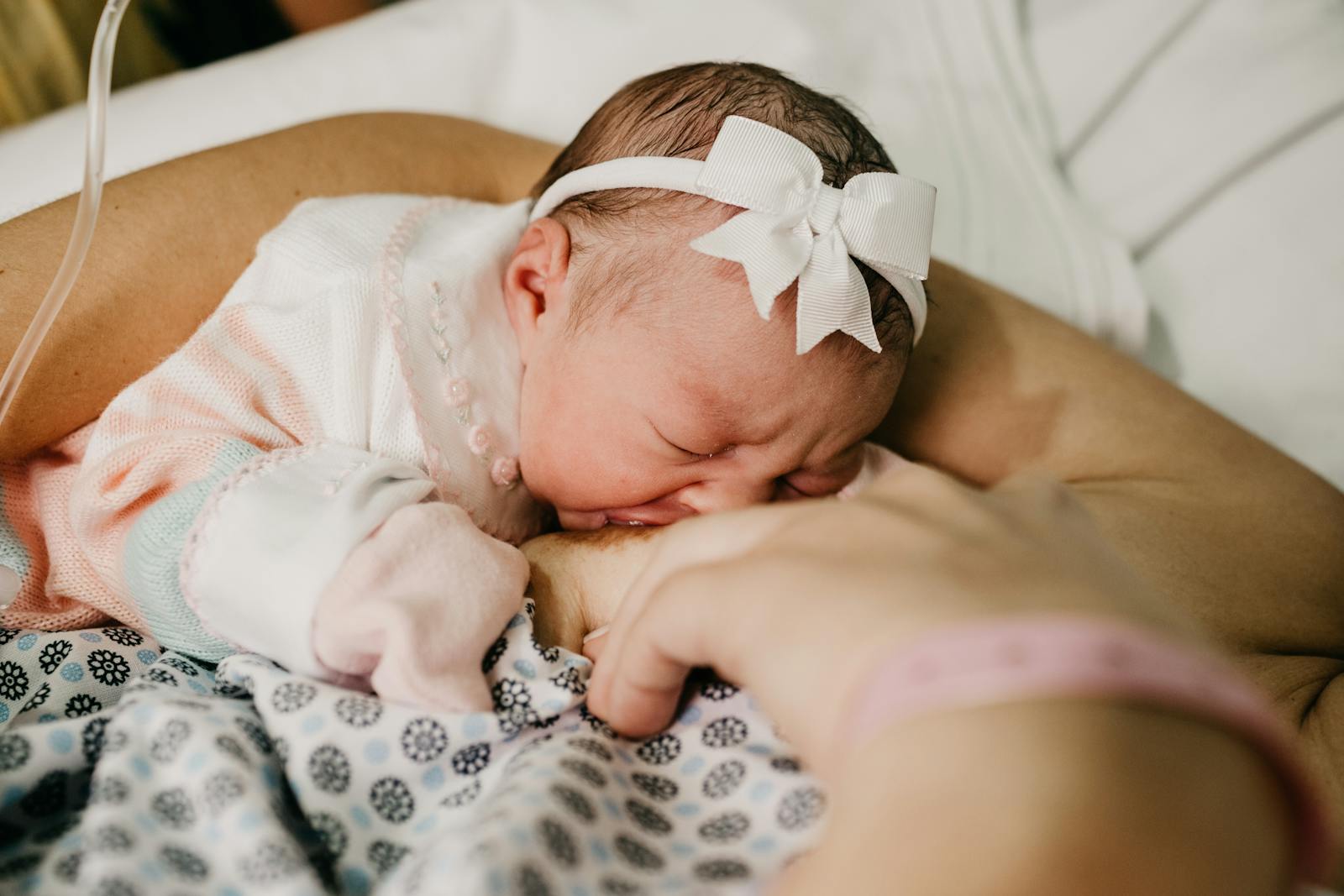 Newborn in a soft headband resting against mother during a calm feed
