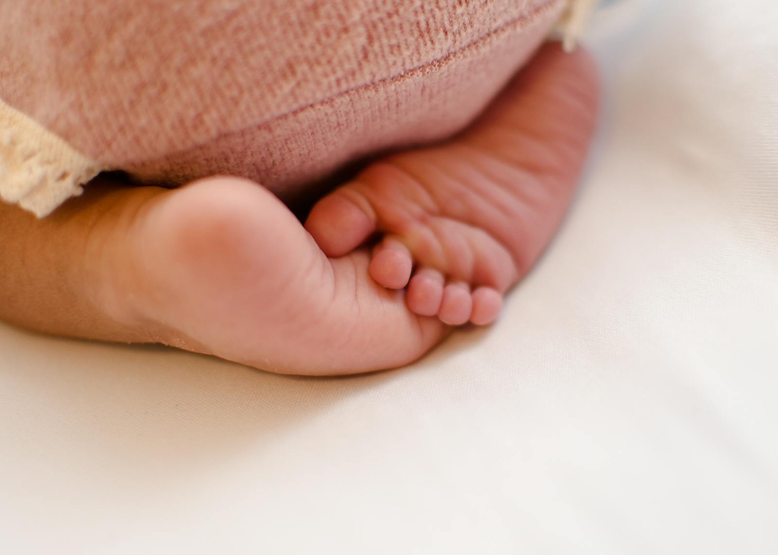 Newborn baby feet resting on a soft blanket