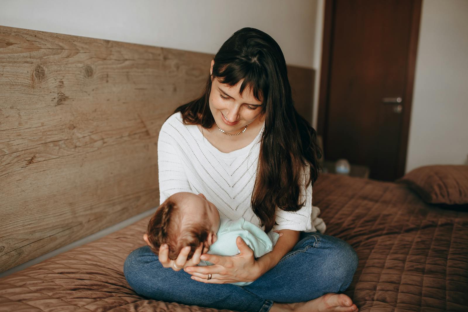 Mother gently holding her sleeping newborn baby, warm natural light