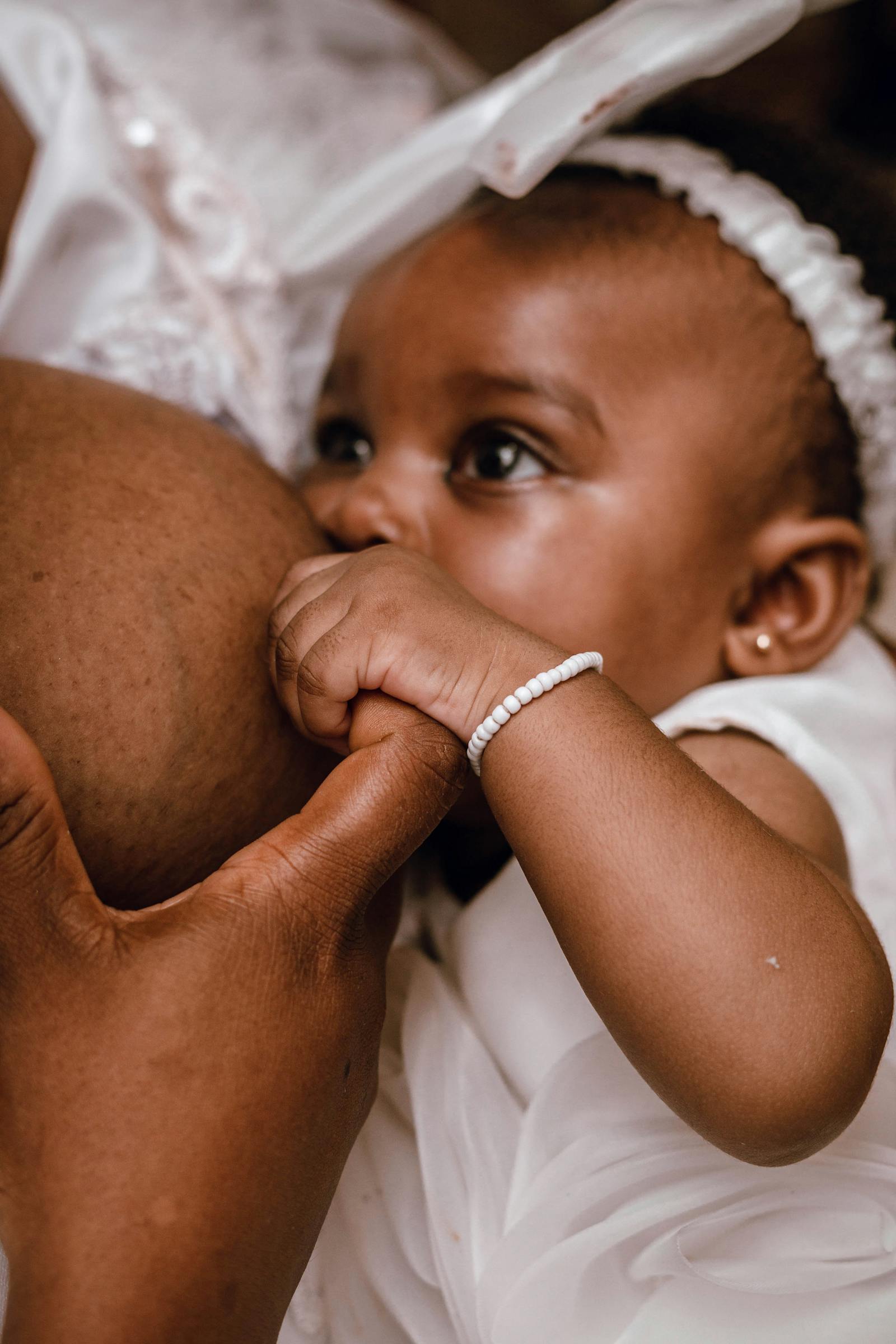 Close-up of a newborn baby latched and nursing, looking alert at the camera