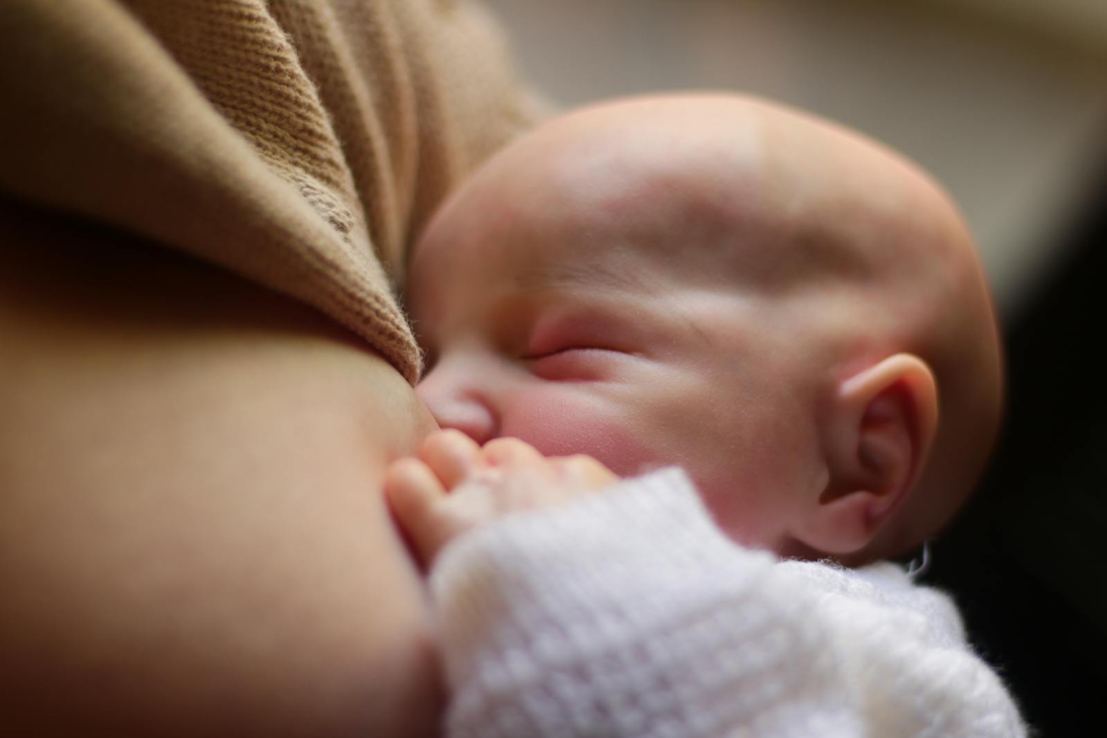 Close-up of a newborn breastfeeding with mouth wide open and lips flanged out