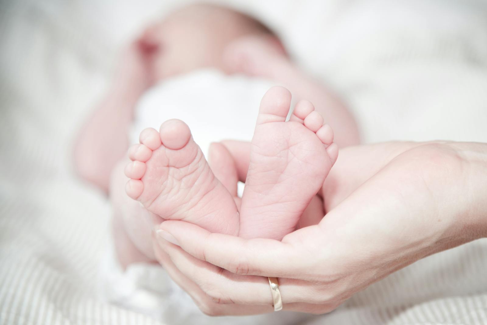 Mother's hands gently holding her newborn baby's tiny feet