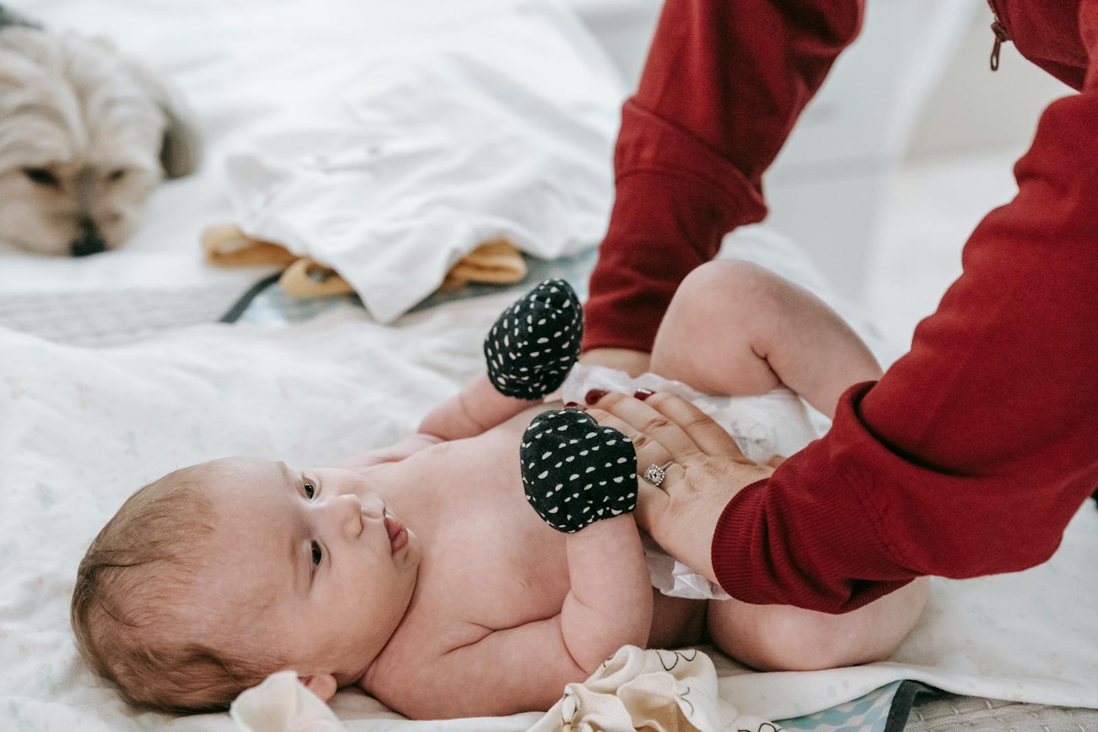 A mother gently changing her baby's diaper on a soft mat in a cozy nursery