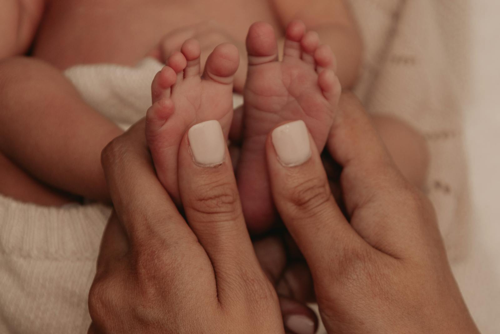 A mother gently holding her newborn's feet, a quiet moment of reassurance